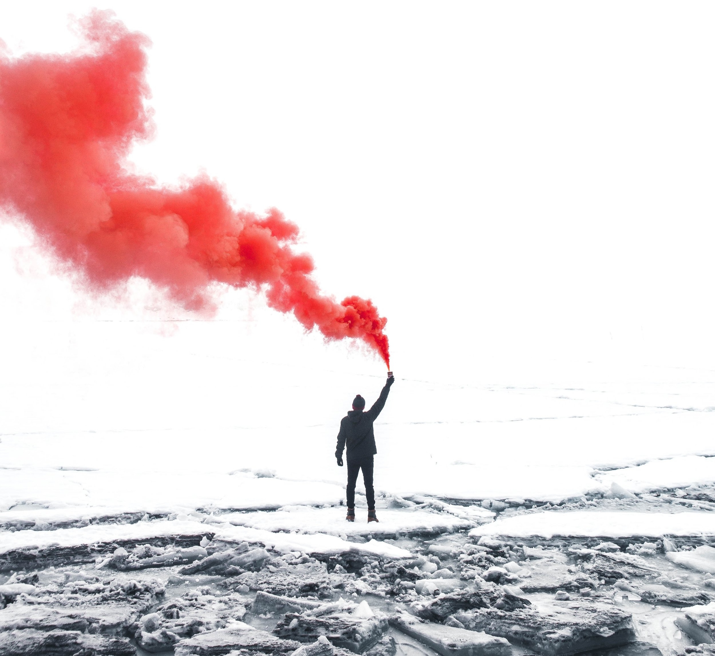 person holding a red smoke grendade standing on ice