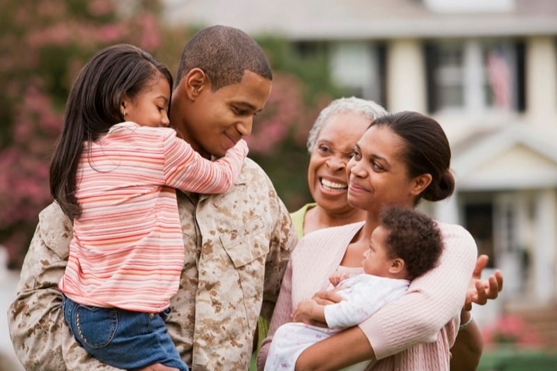 family holding each other and smiling with soldier father