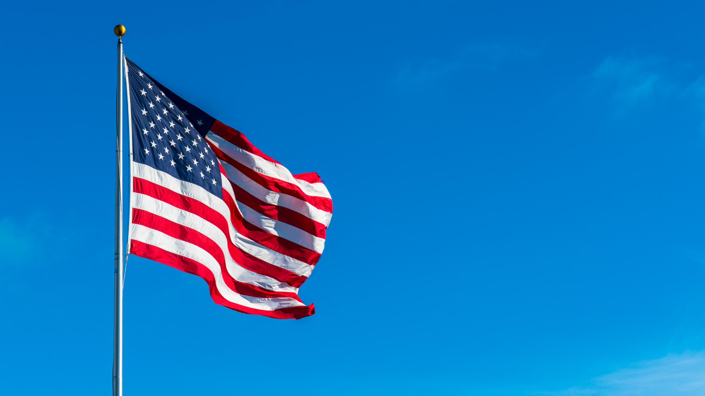 American flag flowing over blue sky