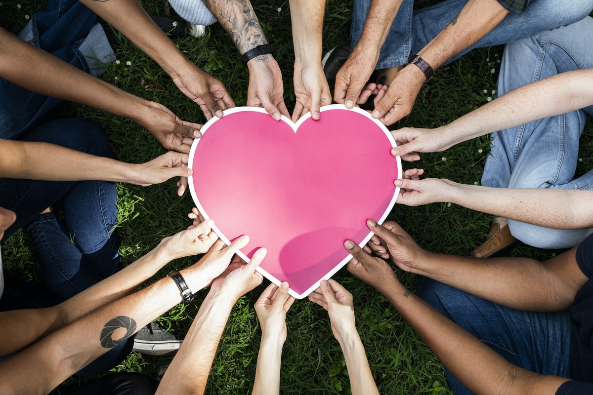 group of people holding a paper heart together