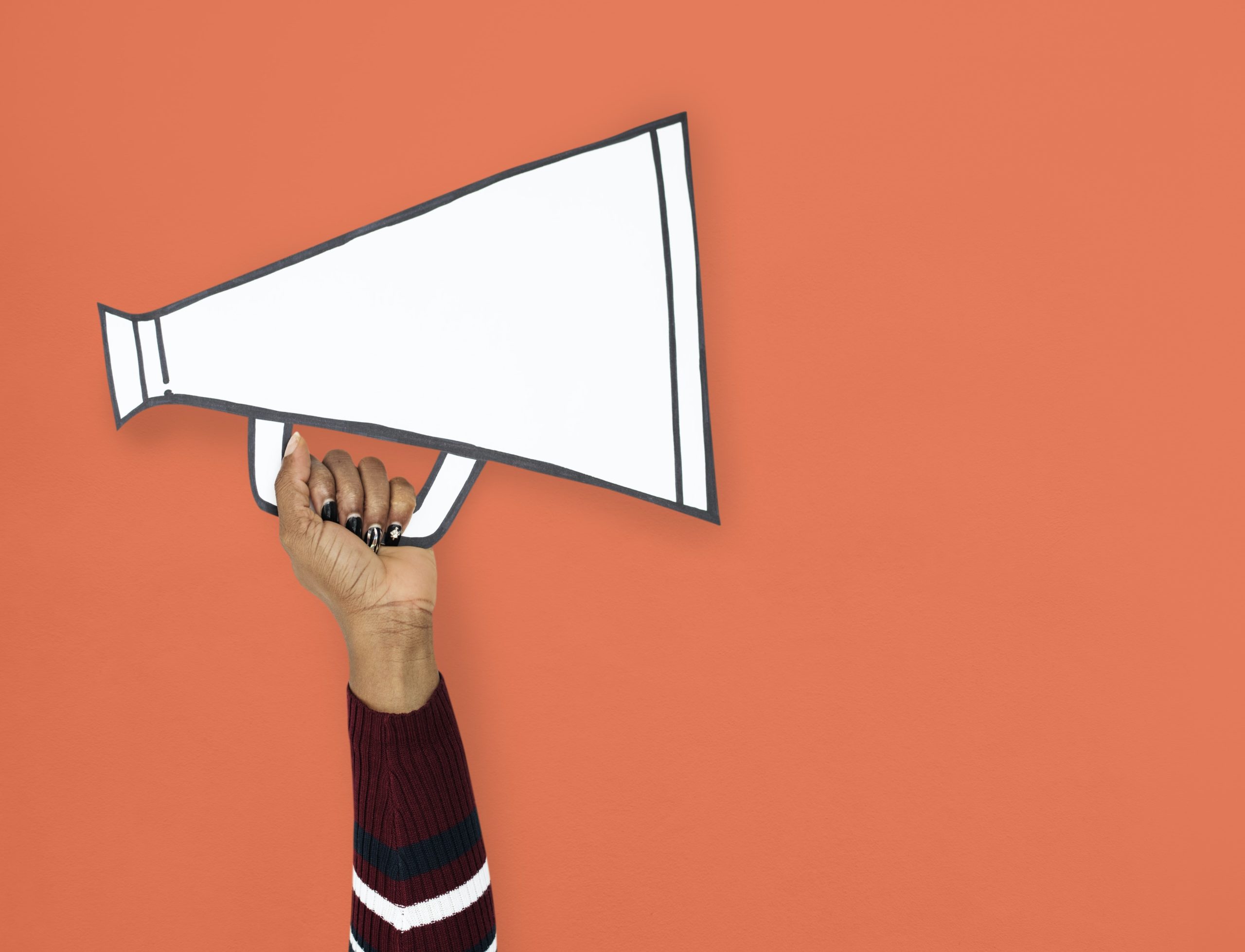 person holding paper megaphone over orange background