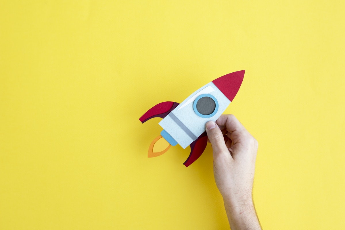 person holding felt rocketship over yellow background