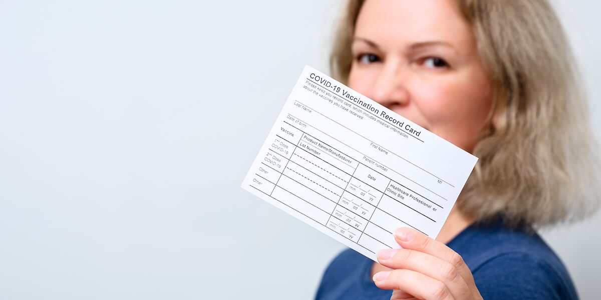 Vaccinated woman showing COVID-19 Vaccination Record Card