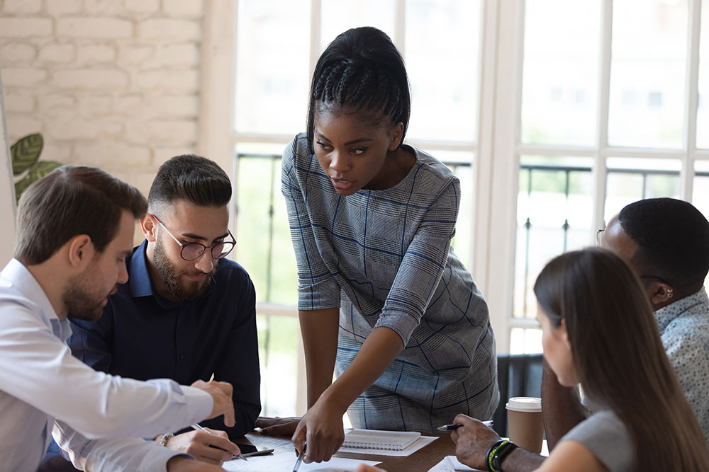 Diverse group of working professionals talking around a table.