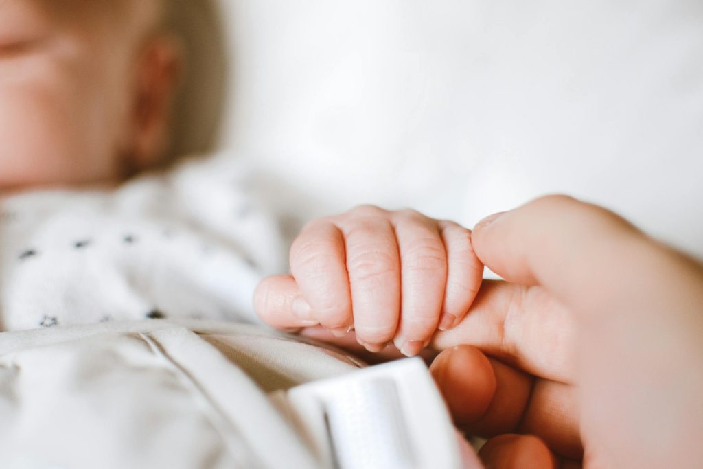 Close-up of a newborn's hand gently gripping a parent's finger, symbolizing love and connection.