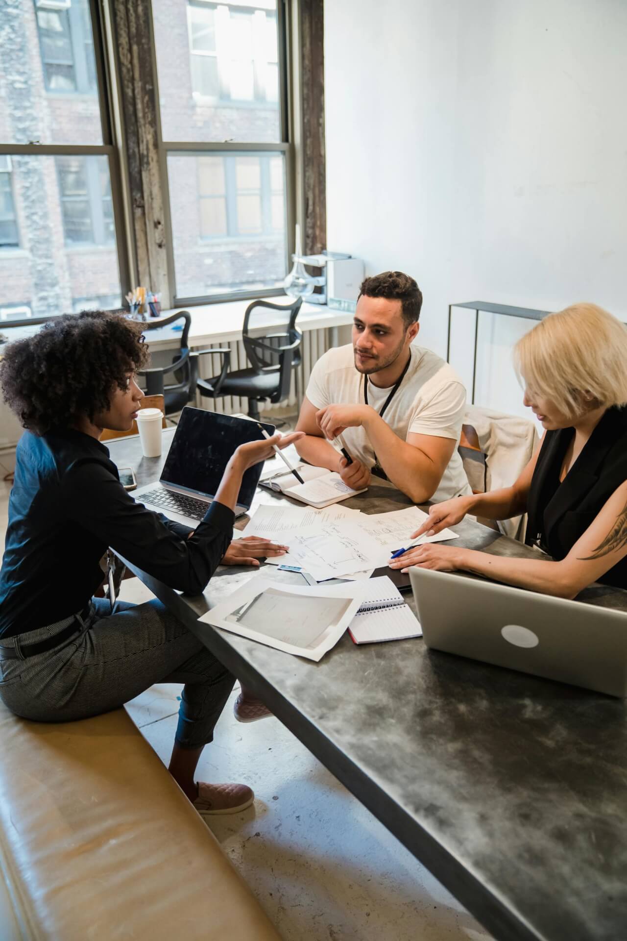 A diverse group of professionals engaged in discussion around a table in a modern office setting.