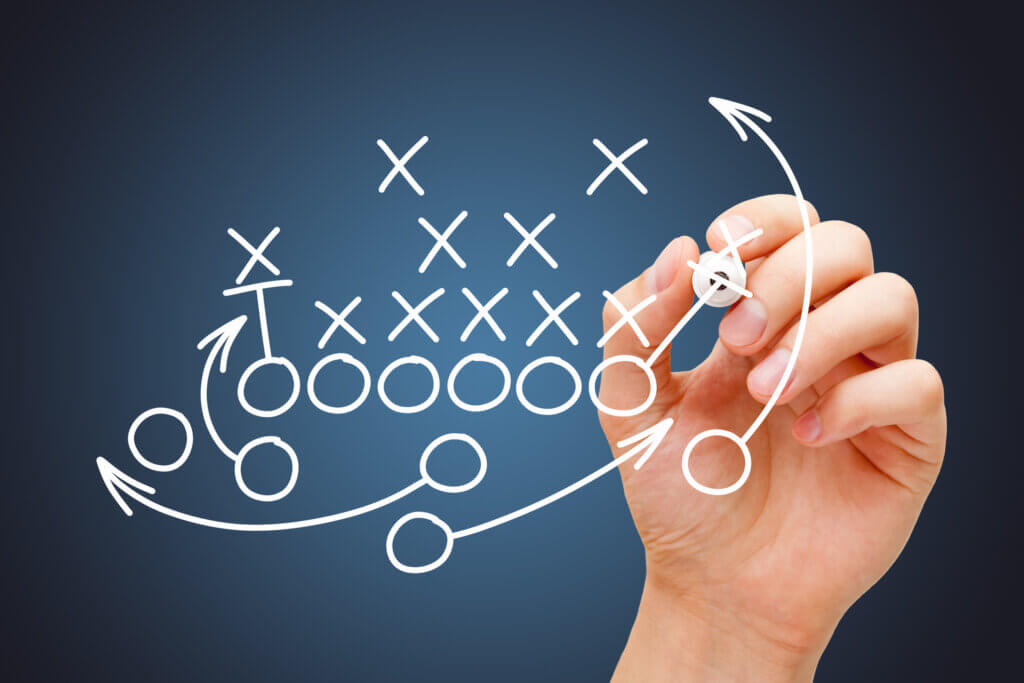 Hand drawing American football or rugby game playbook, strategy and tactics with white marker on blue background.